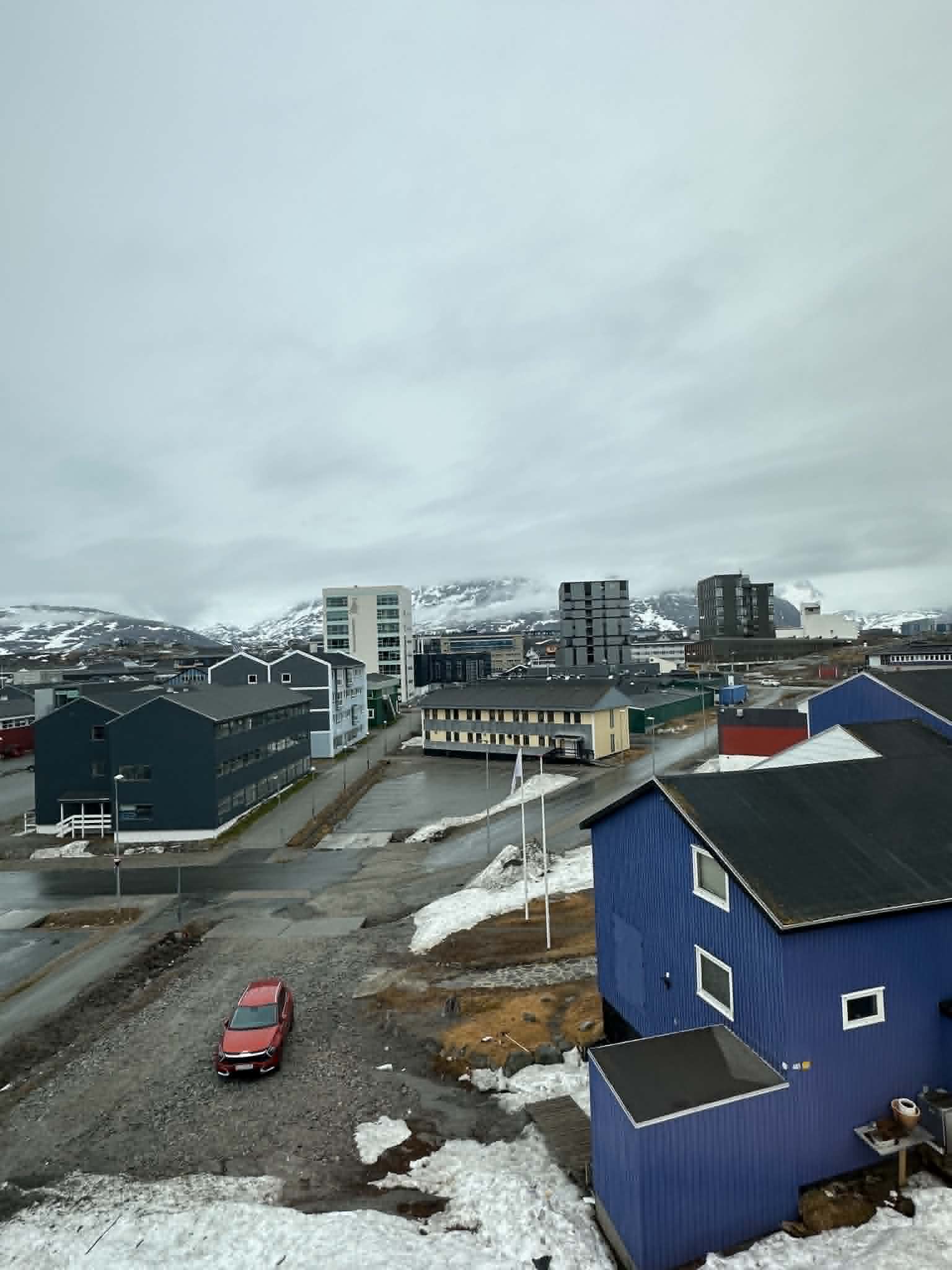 View of Nuuk town with modern apartment buildings and snow-capped mountains