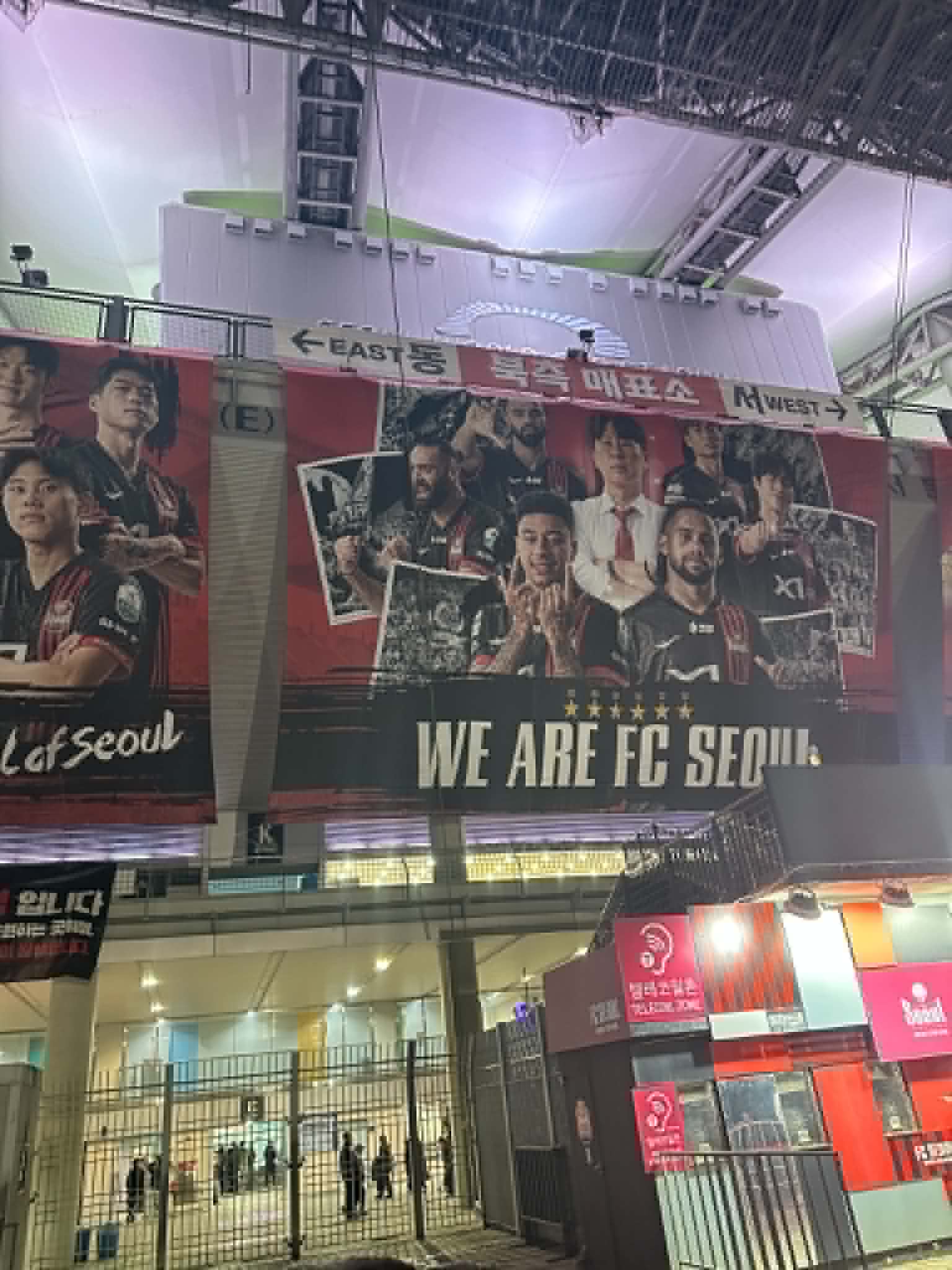 FC Seoul stadium entrance banner reading WE ARE FC SEOUL with player faces including Jesse Lingard