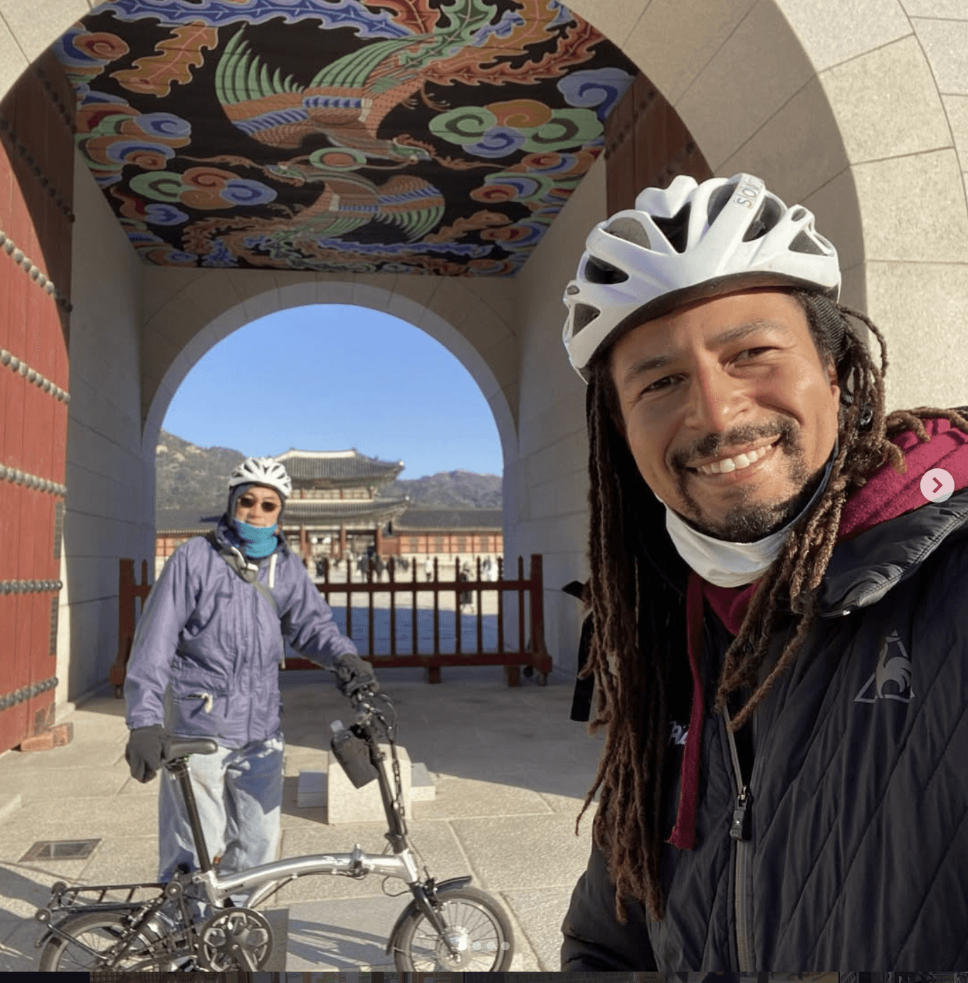 Vincent of WeRide Korea in a white helmet at Gyeongbokgung Palace, with a painted gate ceiling visible above and the palace through the archway behind